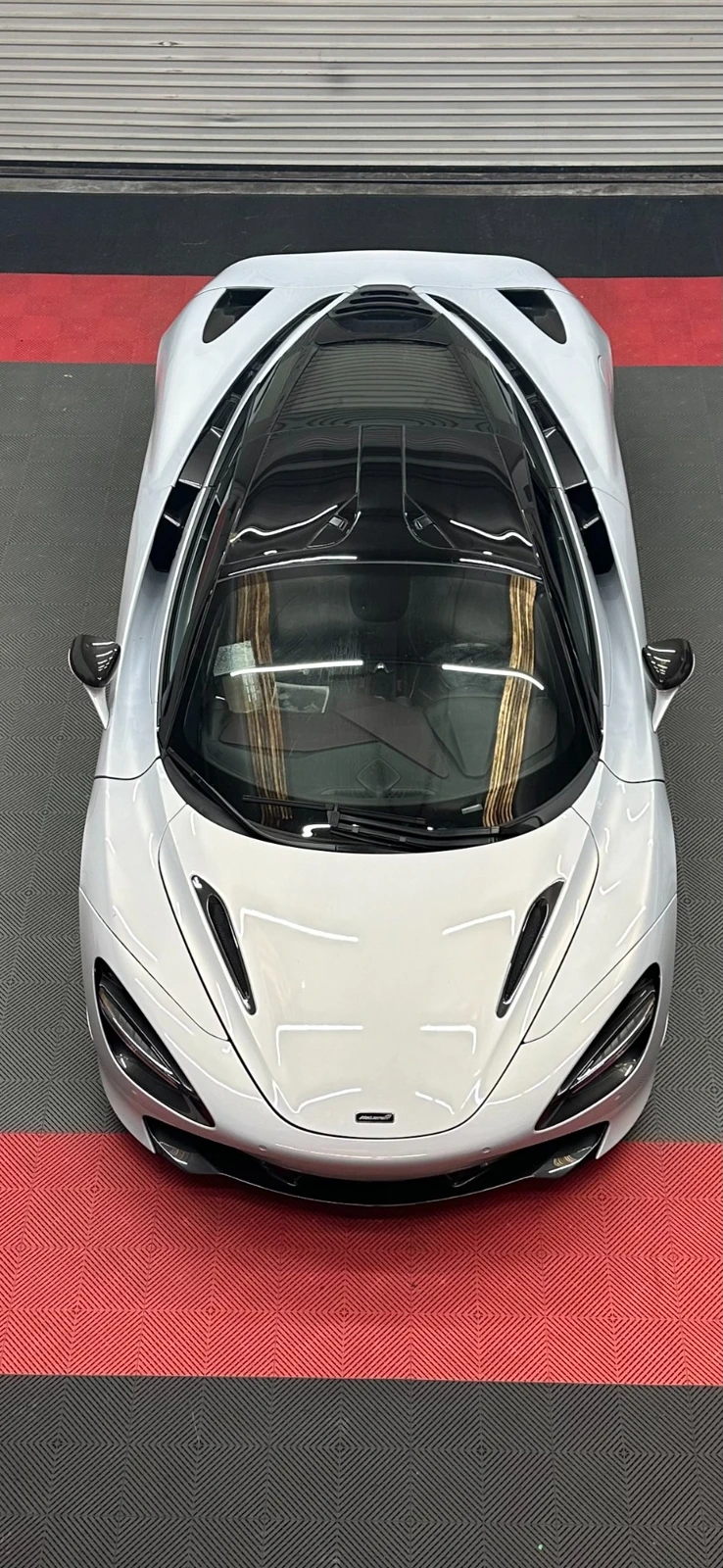 Overhead view of a silver McLaren on the red and black floor at Pro Dent’s Hoover shop