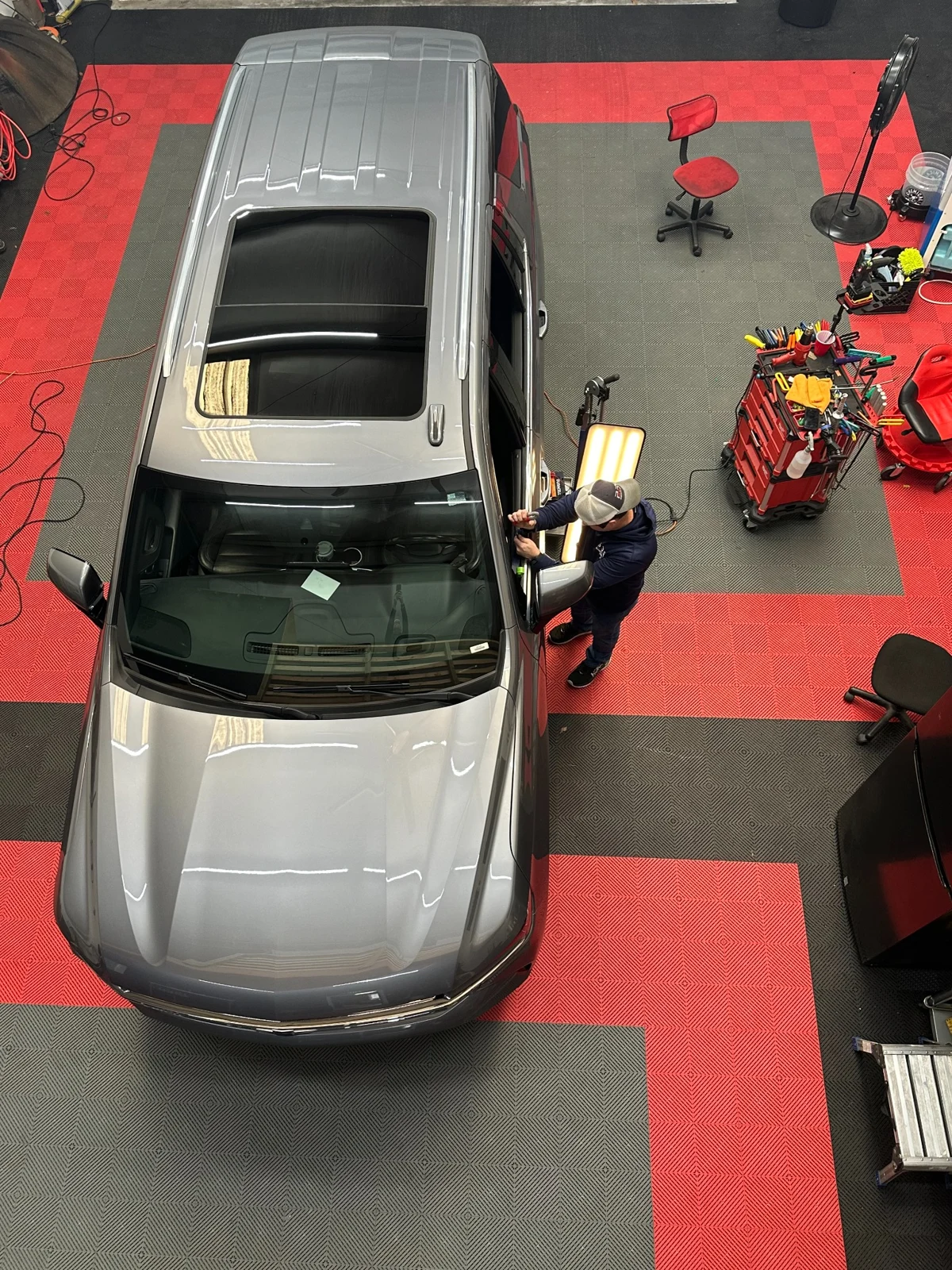 Overhead view of a Pro Dent technician performing paintless dent repair on a silver SUV in the Hoover shop